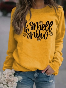 Detail of loose fit yellow crewneck sweatshirt featuring I smell snow graphic and floral accent
