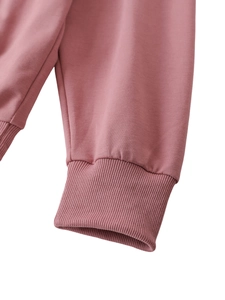 Dettaglio dei polsini a costine elasticizzate sulla manica di una felpa rosa antico