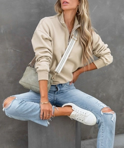 Dettaglio felpa beige con mezza zip con colletto rialzato e polsini a costine rifiniti