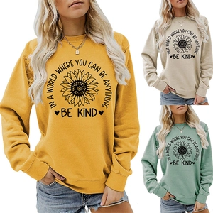 Detailed view of the sunflower print and 'Be Kind' slogan on crewneck sweatshirts