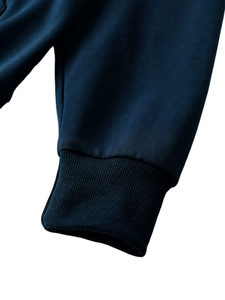 Dettaglio del polsino in maglia a coste blu scuro su felpa con cappuccio di pregio