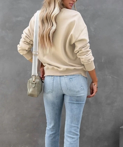 Vista posteriore di una felpa beige a maniche lunghe con jeans blu effetto invecchiato