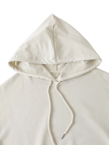 Dettaglio felpa con cappuccio beige con focus sulla trama del tessuto e terminali in metallo