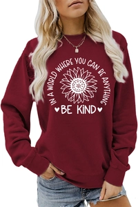Detail of sunflower print and 'Be Kind' text on burgundy crewneck long sleeve sweatshirt