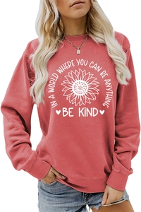 Close-up of the sunflower print and Be Kind slogan on the brick red crewneck sweatshirt