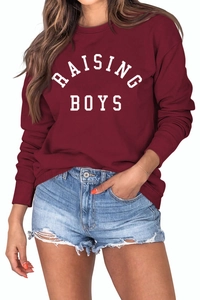 Close-up of Raising Boys lettering on burgundy long sleeve crewneck sweatshirt texture
