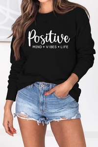 Détail de l'imprimé à lettres positive mind vibes life sur un sweat-shirt noir à manches