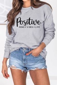 Détail du lettrage Positive Mind Vibes Life sur le sweat à col rond gris clair