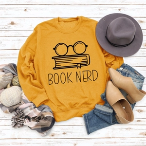 Flat lay of a mustard yellow sweatshirt with Book Nerd glasses print and autumn styling