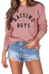 Detailed macro view of the RAISING BOYS text print on a pink crewneck cotton sweatshirt