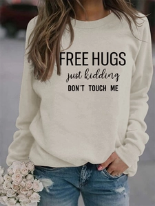 Detail of Free Hugs slogan printed on beige long sleeve sweatshirt and distressed jeans
