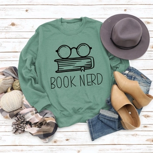 Flat lay of green Book Nerd sweatshirt with glasses print and autumn style accessories