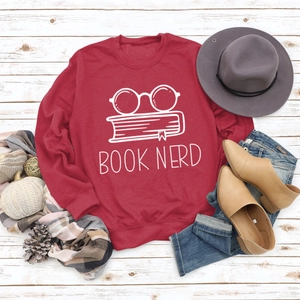 Flat lay of red Book Nerd sweatshirt with glasses print on white wood background