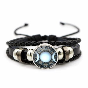 Détail macro du bracelet en cuir tressé avec des breloques argentées de la triple lune