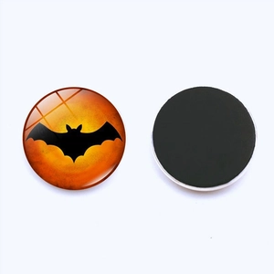 Detail of round Halloween glass fridge magnet showing bat design and black magnetic backing