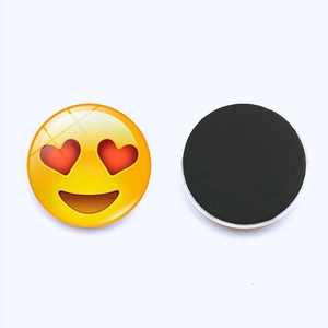 Macro detail of round 25mm glass fridge magnet with heart eyes emoji and black magnetic back