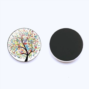 Close-up of glass fridge magnet with colorful tree of life pattern and magnetic backing