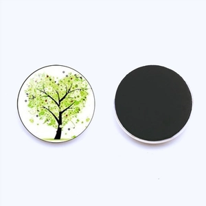 Close-up of circular glass fridge magnets with green Tree of Life pattern and black magnetic back