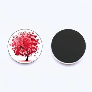 Detail of circular glass fridge magnet showing a pink heart tree and black soft magnetic back