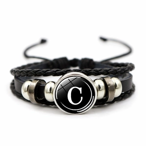 Macro detail of retro multi-layer braided leather bracelet with letter C glass gem