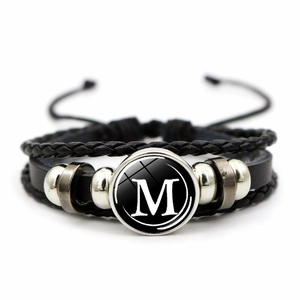 Detailed macro view of multilayer leather bracelet with a glass dome M letter charm