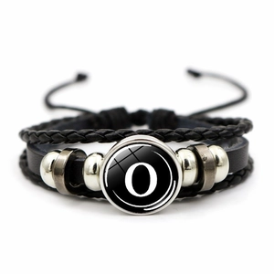 Close-up of multilayer braided leather bracelet with letter O glass dome and alloy beads