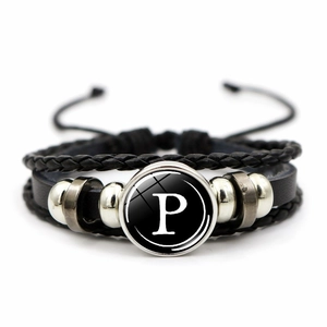 Close-up of multilayer punk bracelet featuring woven leather and a glass letter P charm