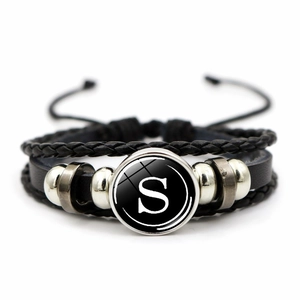 Detail view of multi-layer black leather bracelet with letter S glass pendant charm