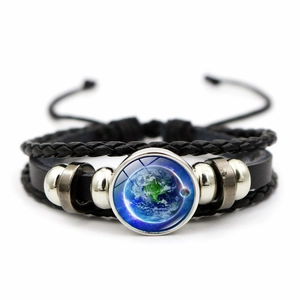 Detail of layered braided leather bracelet featuring a glass dome with Earth pattern charm