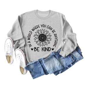 Flat lay of gray crewneck sweatshirt with sunflower print and Be Kind quote with jeans