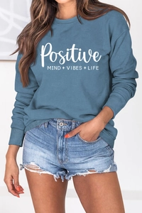 Détail de l'imprimé blanc Positive Mind vibes life sur le sweat-shirt bleu brumeux