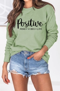 Détail du texte noir 'Positive Mind Vibes Life' imprimé sur un sweat-shirt vert clair