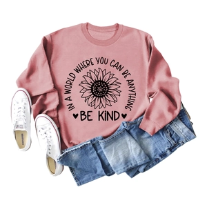 Flat lay of a mauve sweatshirt with sunflower print and 'Be Kind' slogan and denim shorts