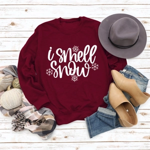 Winter outfit flat lay with i smell snow sweatshirt, scarf, and denim jeans on white wood