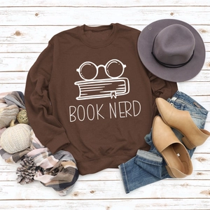 Flat lay of brown Book Nerd sweatshirt styled with autumn accessories on white wood