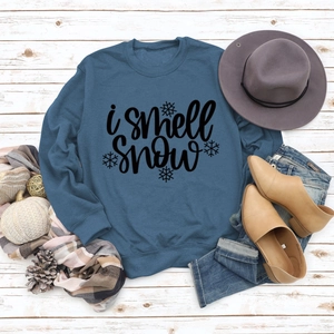 Flat lay of navy blue sweatshirt with I Smell Snow text and autumn accessories on wood