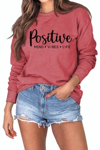 Détail de l'imprimé Positive Mind Vibes Life sur le sweatshirt rouge brique