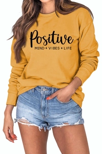 Détail du lettrage Positive Vibes sur le sweat-shirt jaune à manches longues