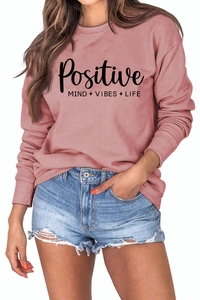 Détail du slogan Positive Vibes imprimé sur un sweat à manches longues rose