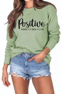 Détail d'un sweat vert clair avec l'inscription Positive Mind Vibes Life imprimée