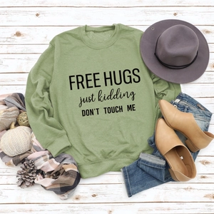 Flat lay of green sweatshirt with Free Hugs slogan and autumn accessories on wood