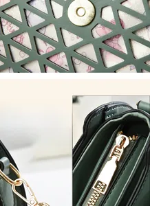 Detail of dark green crossbody bag with gold hardware and laser-cut geometric pattern