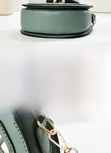 Detailed macro view of green leather bag stitching and golden metal lobster clasp hardware