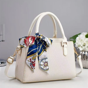 Close-up of white woven handbag with decorative floral silk scarf and gold metal buckle