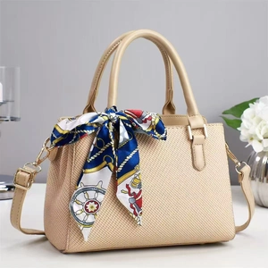 Detail of beige woven handbag with silk scarf, gold hardware, and leather handle