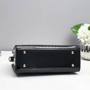 Detail view of black patent leather bag base featuring four golden protective metal studs