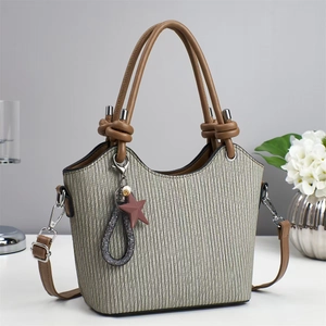 Minimalist grey-green pleated tote bag with brown leather handles and star charm on desk