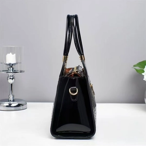 Side view of black glossy patent leather handbag with crocodile pattern and gold D-ring
