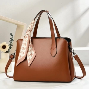 Sac à main en cuir marron pour femme avec foulard décoratif sur fond de studio blanc