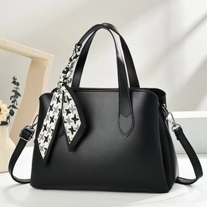 Détail du sac cabas en cuir grainé noir avec un élégant foulard pied-de-poule décoratif